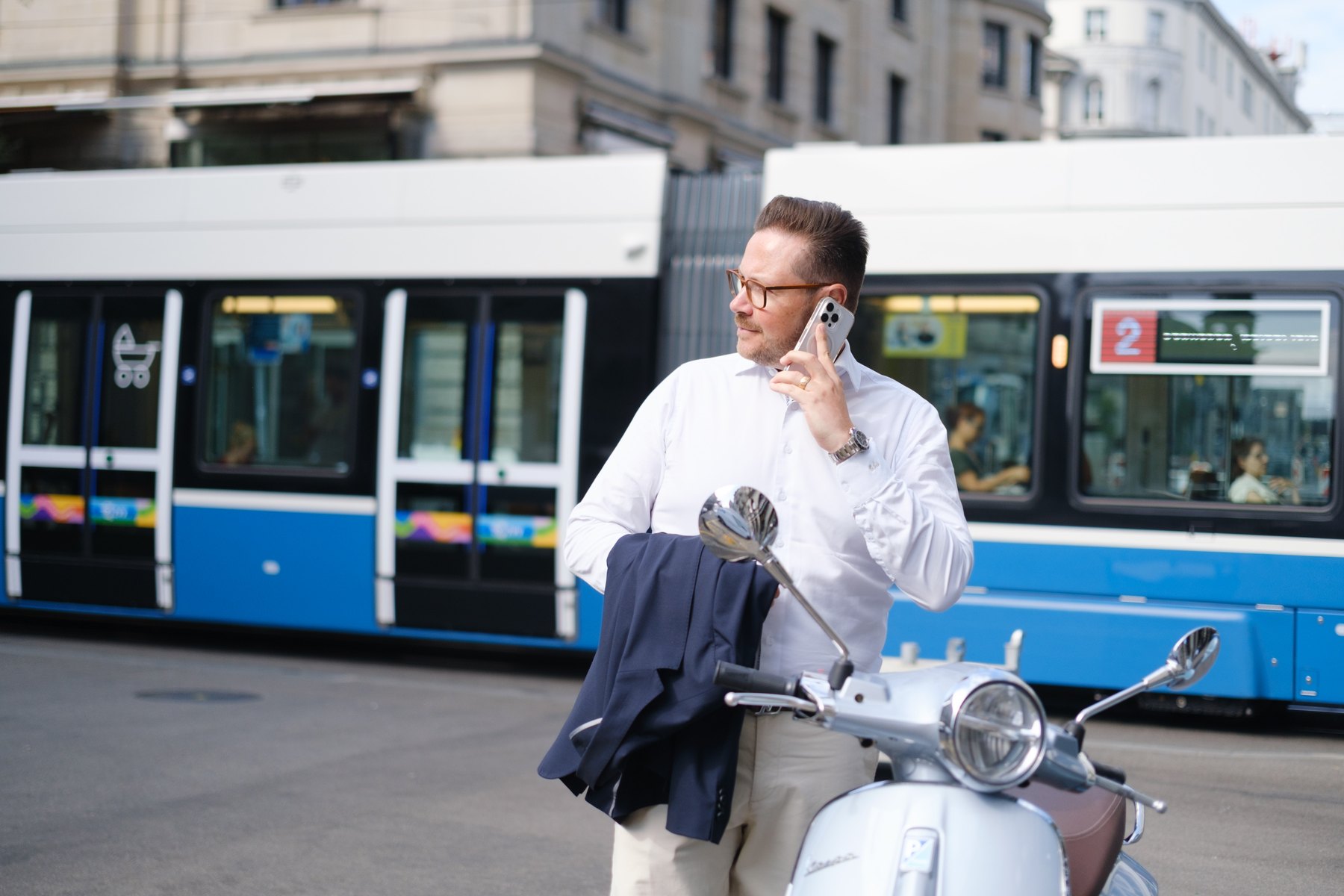 Oliver Gabor telefoniert neben seiner Vespa, hinter ihm fährt ein Zürcher Tram